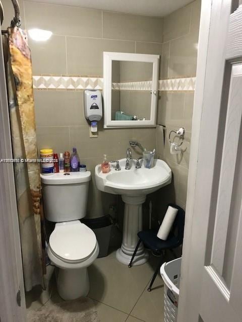 bathroom with toilet, tile walls, and tile patterned floors