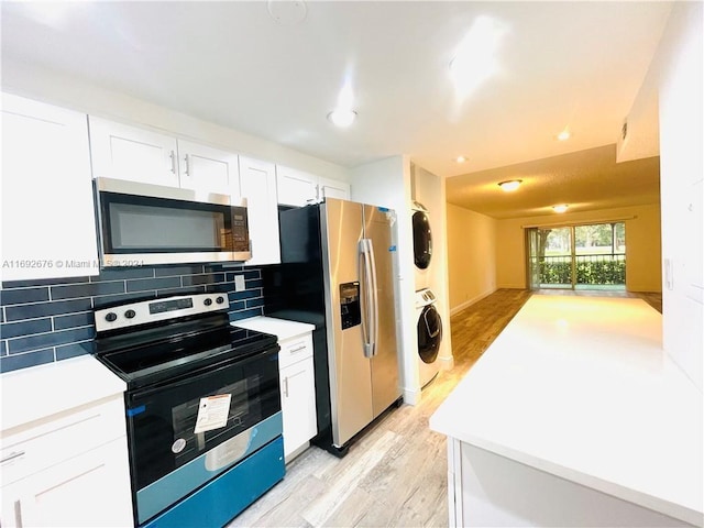 kitchen featuring white cabinets, light hardwood / wood-style flooring, backsplash, appliances with stainless steel finishes, and stacked washer / drying machine