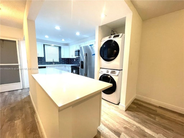 kitchen featuring stacked washer / drying machine, light wood-type flooring, stainless steel appliances, and white cabinets