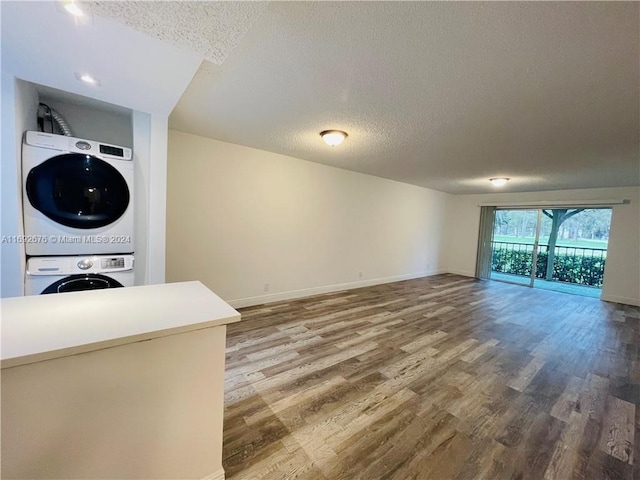 unfurnished living room with hardwood / wood-style floors, stacked washer and clothes dryer, and a textured ceiling