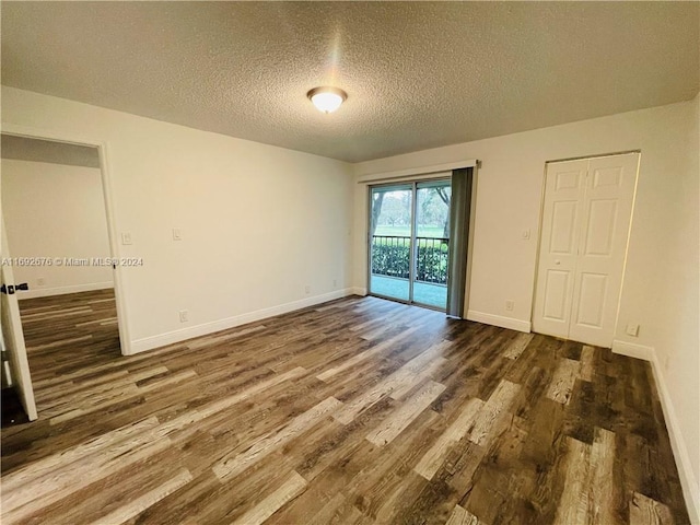 unfurnished room featuring dark wood-type flooring and a textured ceiling