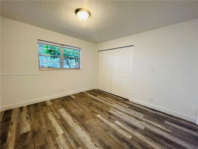 unfurnished bedroom featuring dark hardwood / wood-style flooring, a textured ceiling, and a closet