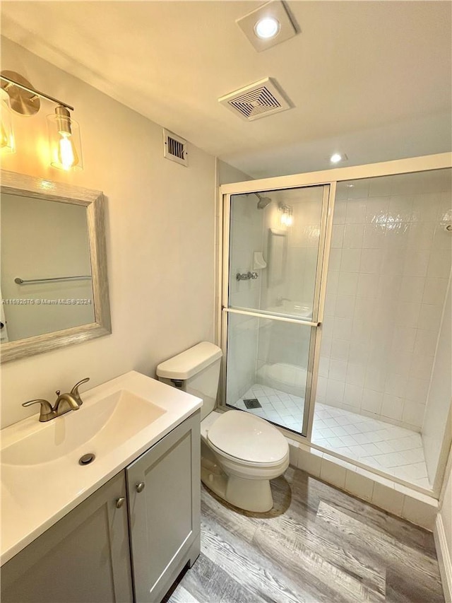 bathroom with toilet, an enclosed shower, vanity, and hardwood / wood-style flooring