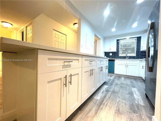 kitchen featuring dark wood-type flooring, white cabinets, decorative backsplash, a textured ceiling, and appliances with stainless steel finishes