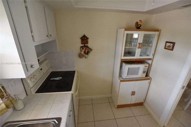 kitchen featuring white cabinets, light tile patterned floors, and white appliances