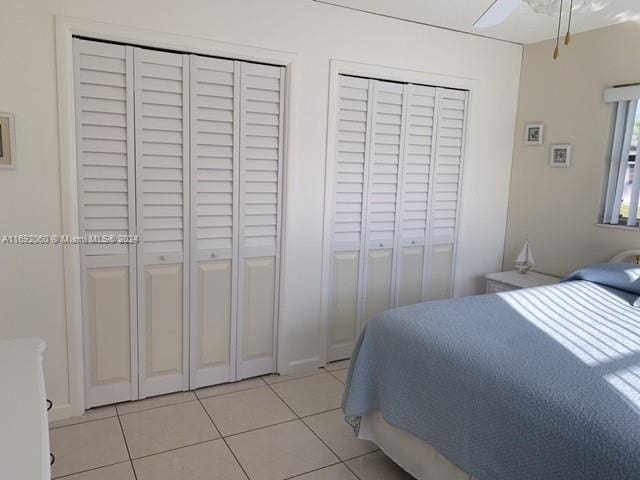 tiled bedroom with two closets and ceiling fan