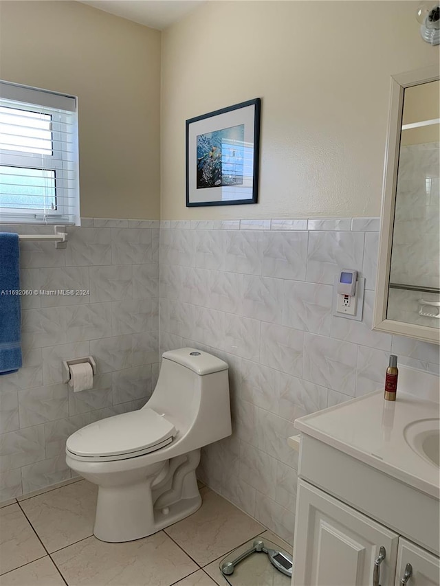 bathroom with tile walls, toilet, vanity, and tile patterned floors