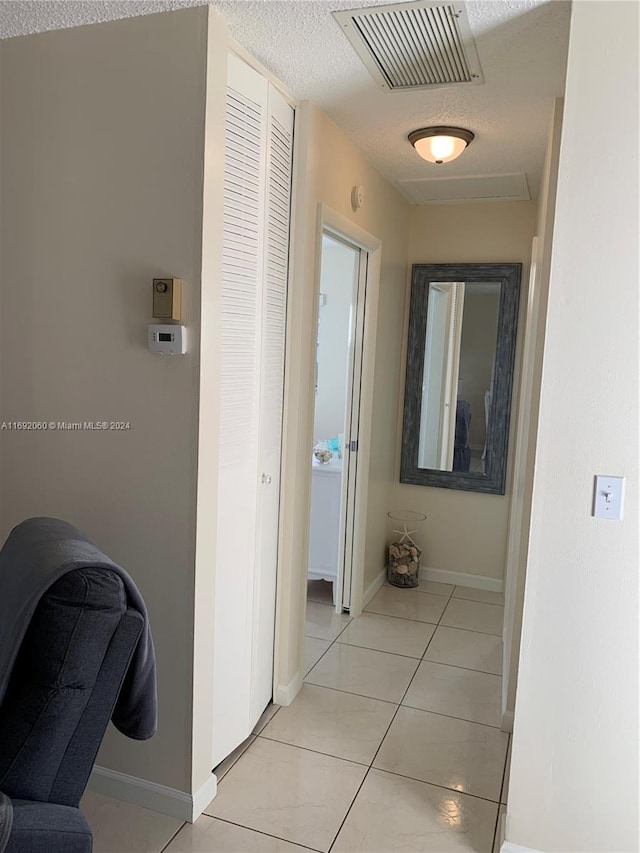 hallway featuring light tile patterned flooring and a textured ceiling