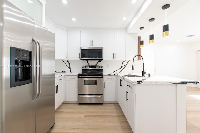 kitchen featuring stainless steel appliances, light hardwood / wood-style floors, white cabinets, and kitchen peninsula