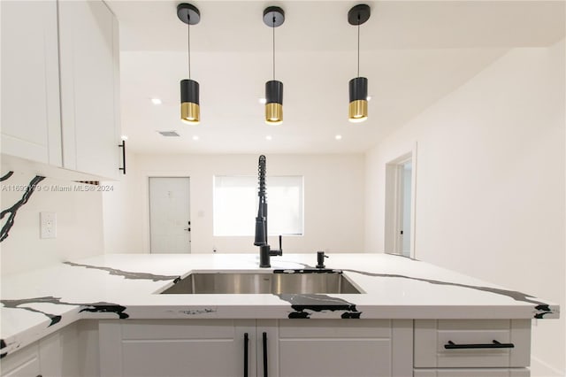 kitchen with white cabinetry, sink, and pendant lighting