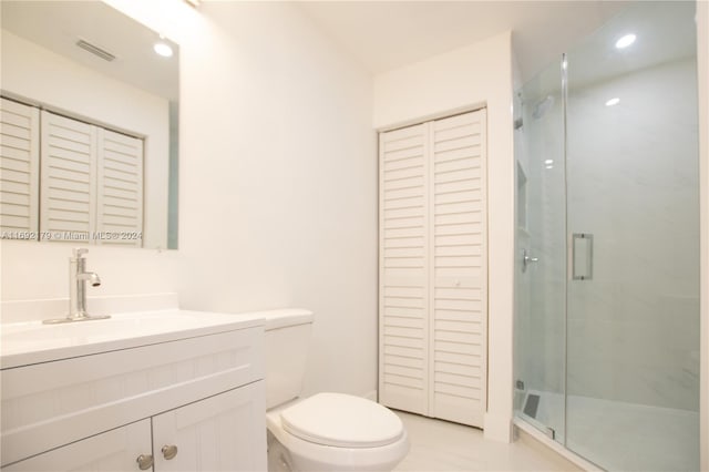 bathroom featuring toilet, vanity, tile patterned flooring, and a shower with shower door