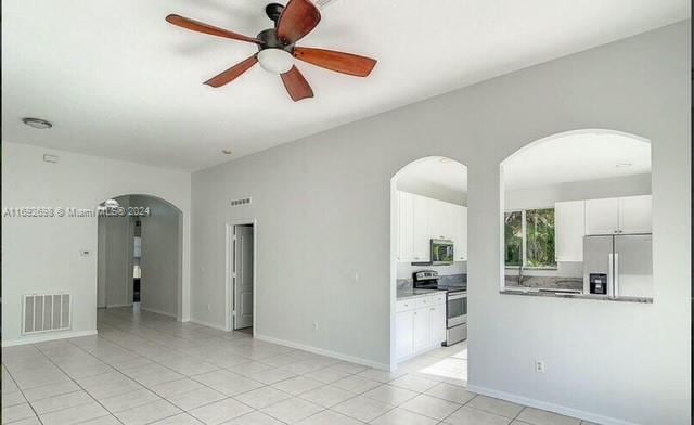 tiled empty room featuring ceiling fan