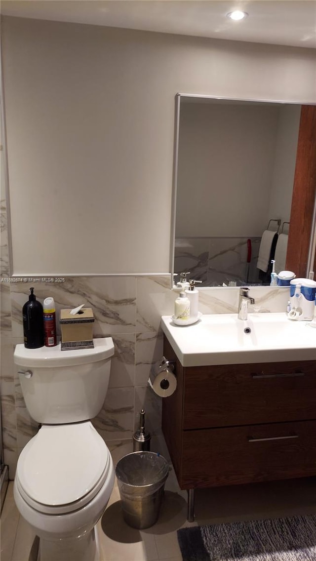 bathroom featuring toilet, wainscoting, tile walls, and vanity