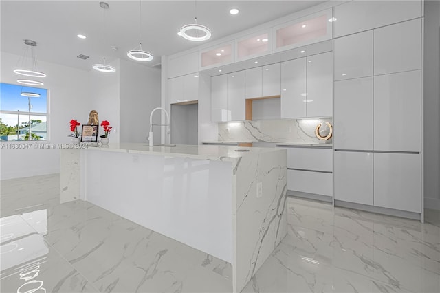 kitchen featuring a center island with sink, white cabinets, hanging light fixtures, and sink