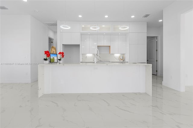 kitchen featuring white cabinets, sink, hanging light fixtures, and a kitchen island with sink