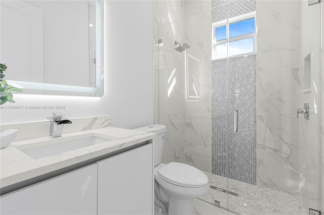 bathroom featuring a shower with door, vanity, and toilet