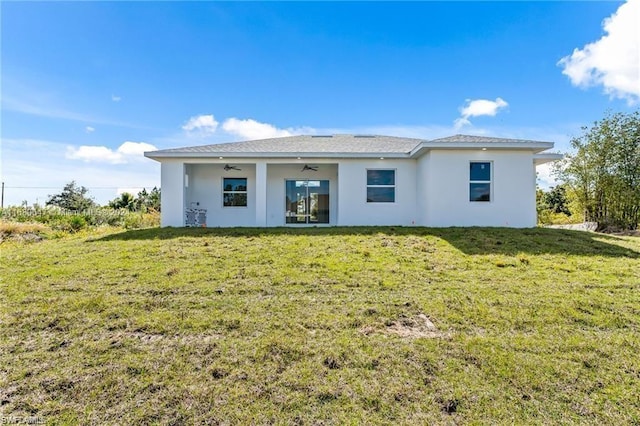 rear view of house featuring ceiling fan and a yard