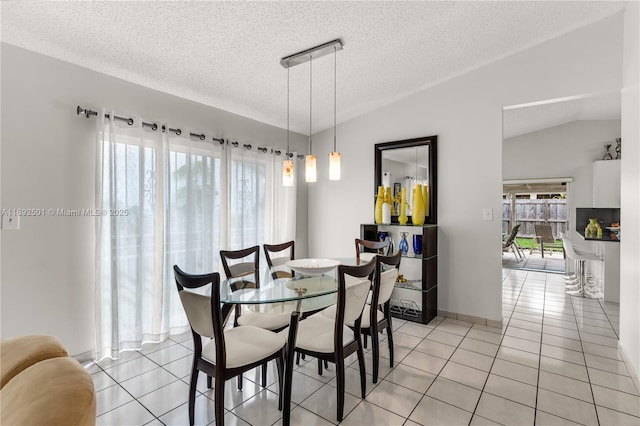 tiled dining area with a textured ceiling, a wealth of natural light, and lofted ceiling