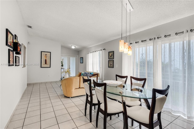 dining area featuring light tile patterned floors, a textured ceiling, french doors, and lofted ceiling