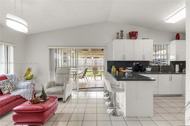 kitchen with backsplash, white cabinetry, light tile patterned floors, and lofted ceiling