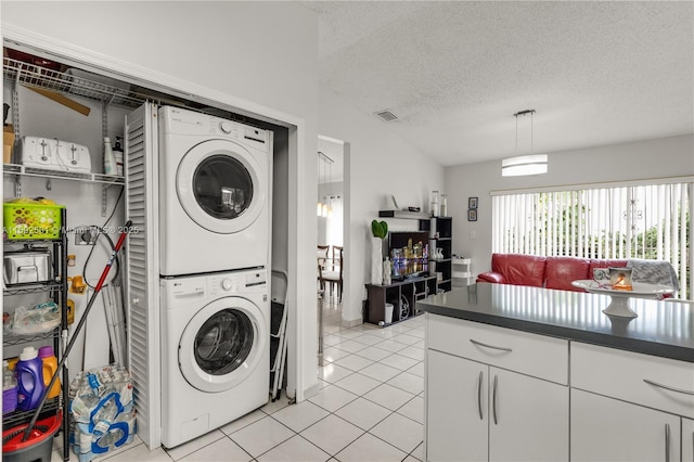 washroom with light tile patterned floors, a textured ceiling, and stacked washer / dryer