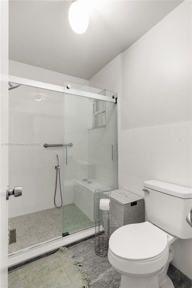 bathroom featuring walk in shower, toilet, and tile walls