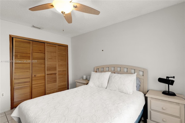 tiled bedroom with ceiling fan, a textured ceiling, and a closet