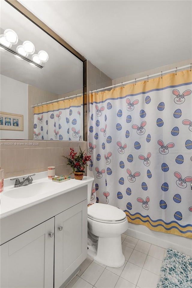 bathroom with tasteful backsplash, vanity, tile walls, tile patterned flooring, and toilet