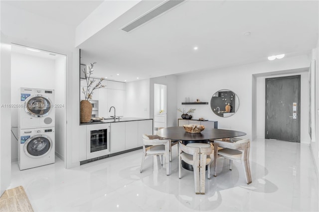 tiled dining area with stacked washing maching and dryer, sink, and wine cooler