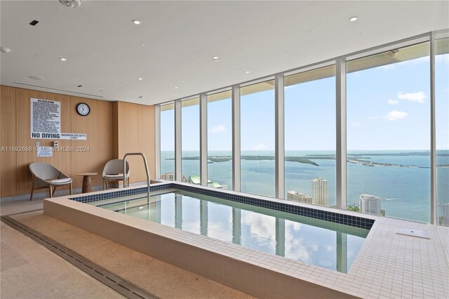 view of pool featuring a water view and a jacuzzi