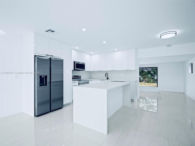 kitchen featuring stainless steel appliances, white cabinetry, sink, and a center island