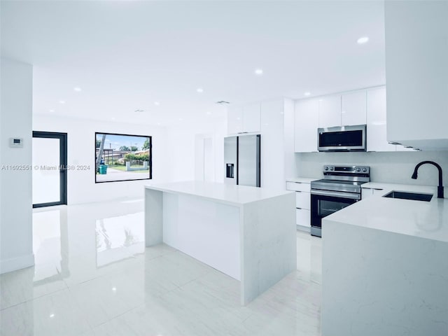 kitchen with a center island, appliances with stainless steel finishes, sink, and white cabinets