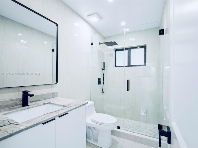 bathroom with toilet, vanity, and a shower with door