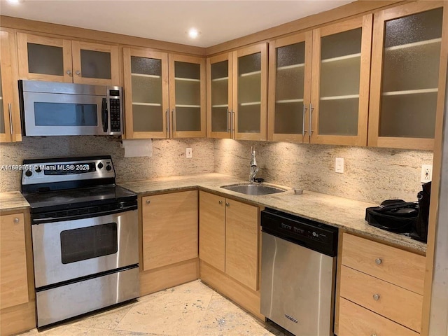 kitchen featuring appliances with stainless steel finishes, sink, light stone counters, and backsplash