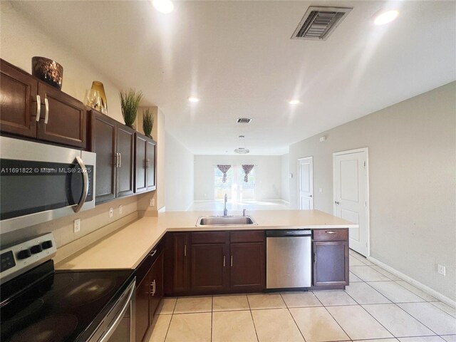 kitchen featuring dishwasher, kitchen peninsula, sink, light tile patterned floors, and dark brown cabinets