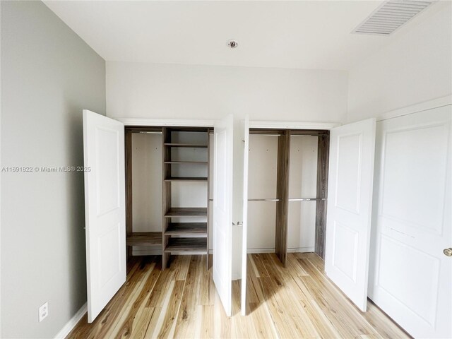 clothes washing area featuring stacked washer and dryer and light wood-type flooring