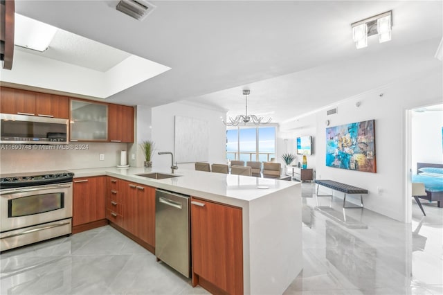 kitchen featuring stainless steel appliances, an inviting chandelier, kitchen peninsula, hanging light fixtures, and sink