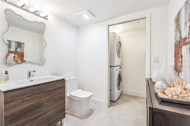 bathroom featuring tile patterned flooring, vanity, stacked washer / dryer, and toilet