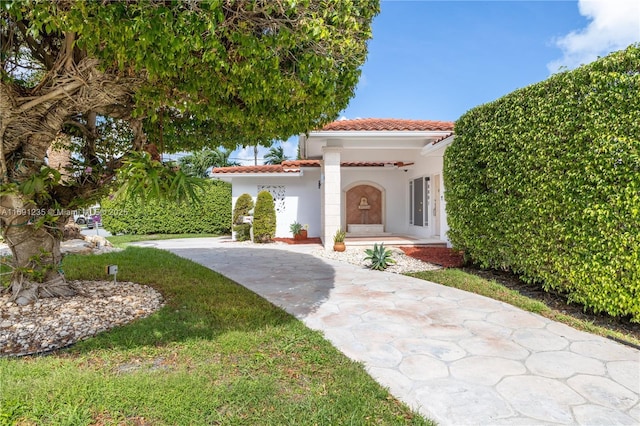 view of front of property featuring a tiled roof, a front yard, and stucco siding