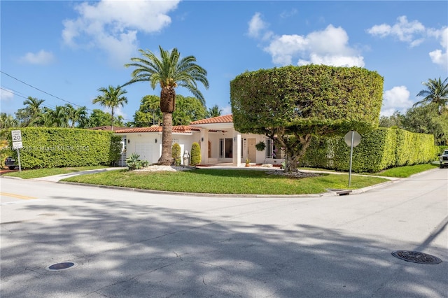 mediterranean / spanish home featuring a tiled roof, a front lawn, and stucco siding