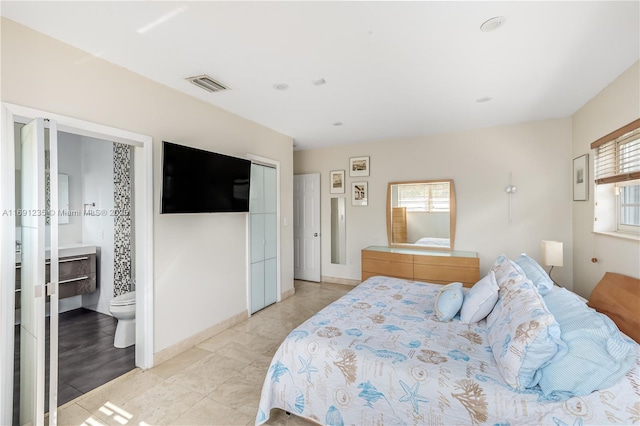 bedroom with light tile patterned floors, connected bathroom, and visible vents