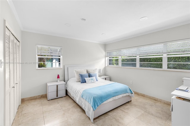 bedroom featuring light tile patterned floors, baseboards, ornamental molding, and a closet