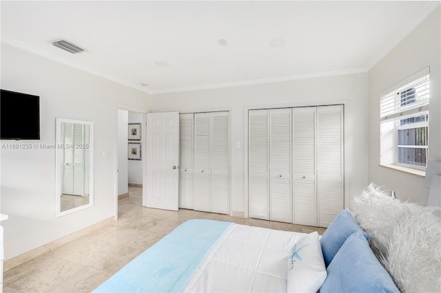 bedroom with visible vents, ornamental molding, and two closets