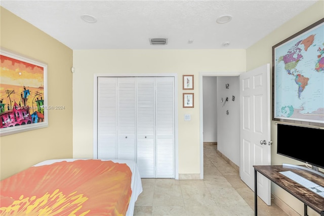 tiled bedroom with a textured ceiling and a closet