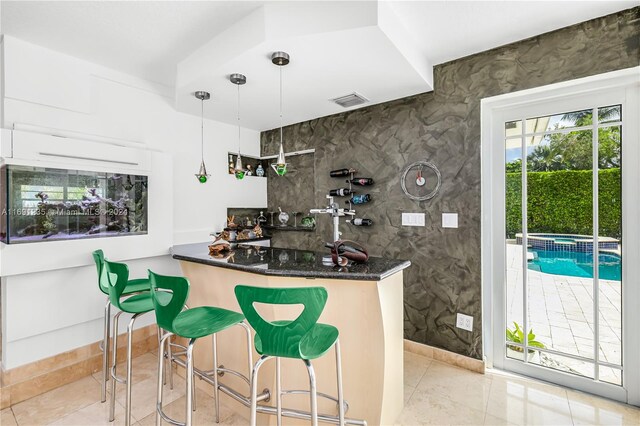 bar with dark stone counters, white cabinetry, light tile patterned flooring, and pendant lighting