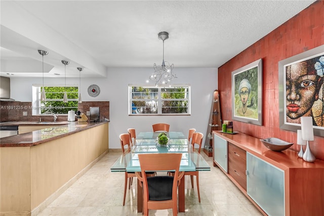 dining room with sink, a chandelier, and a textured ceiling