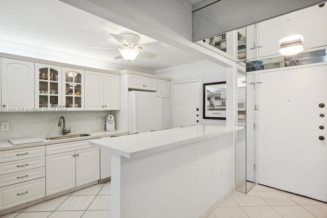 kitchen featuring white refrigerator, white cabinets, sink, light tile patterned floors, and ornamental molding