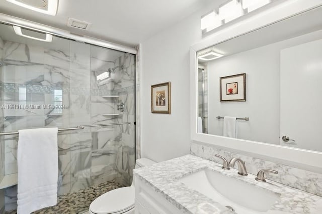 bathroom featuring toilet, vanity, and an enclosed shower