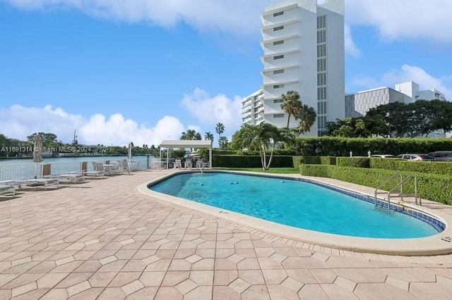 view of swimming pool featuring a patio area and a water view