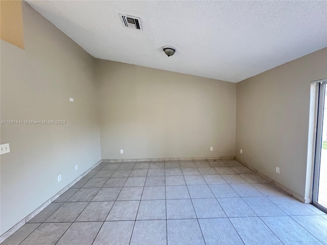 unfurnished room featuring a textured ceiling, a wealth of natural light, and light tile patterned floors